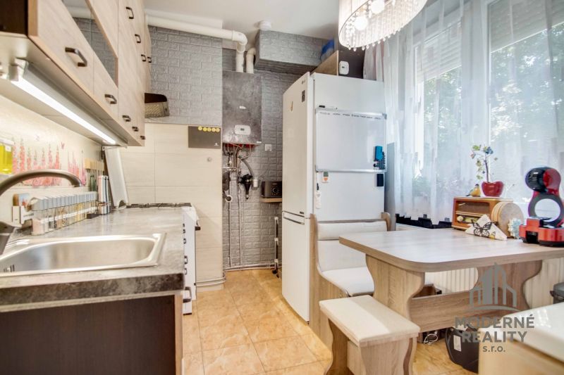 Küche in einer 2-Zimmer-Wohnung mit Geräten, Essecke und dekorativer Ziegelwand.