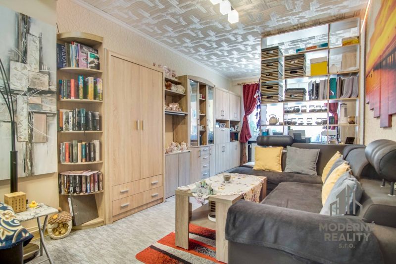 Wohnzimmer mit Bücherregal, Sofa und Holzboden in einer Zweizimmerwohnung.