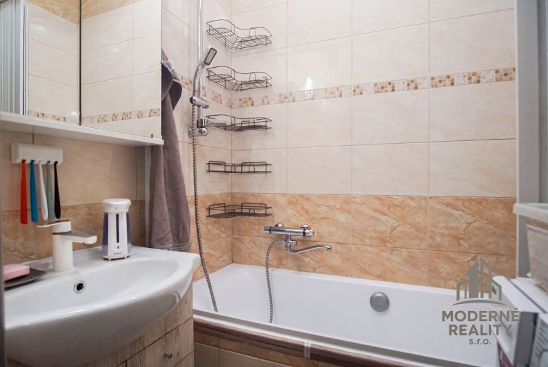 Badezimmer in einer 2-Zimmer-Wohnung mit Badewanne, Dusche und Wandregalen.