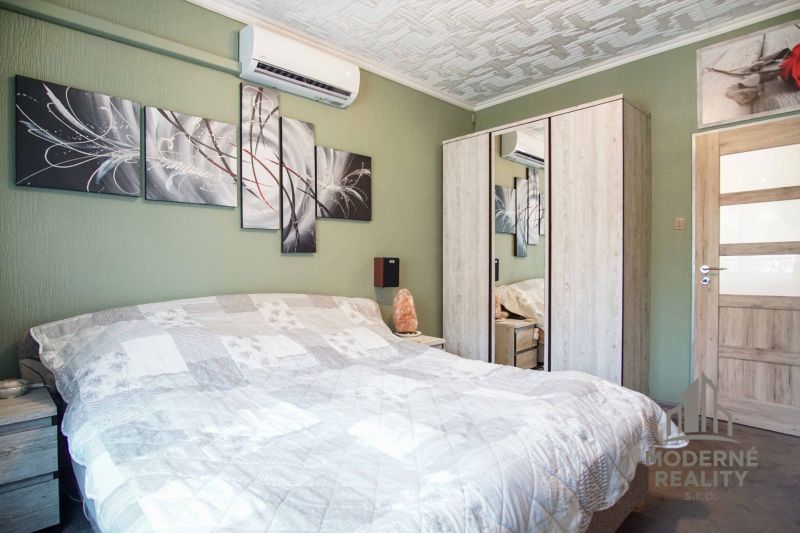Schlafzimmer in einer 2-Zimmer-Wohnung mit Klimaanlage und Kunst an der grünen Wand.