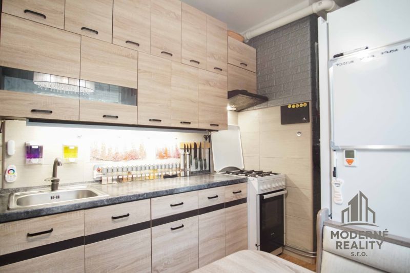 Küche in einer 2-Zimmer-Wohnung mit Holzdekor-Schränken und einem Gasherd.