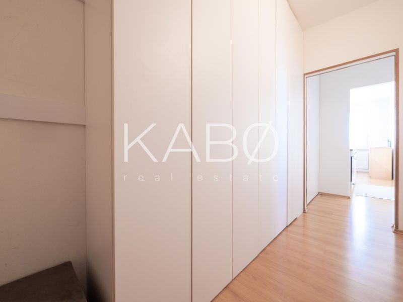 Flur mit einem Schrank und einem Boden mit Holzdekor in einer 2-Zimmer-Wohnung.