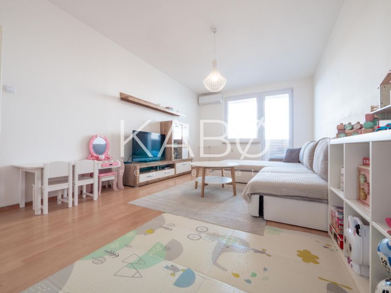 Wohnzimmer in einer 2-Zimmer-Wohnung mit Holzboden, Kindermöbeln und Sofa.