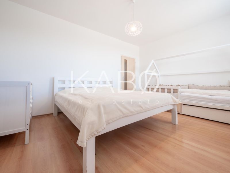 Schlafzimmer mit Holzboden, Doppelbett und Kinderbett.