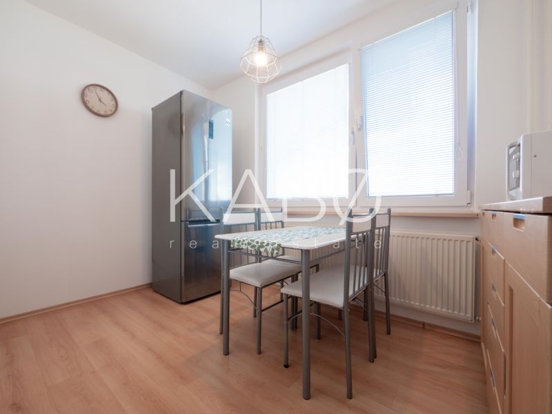 Küche mit Holzboden, Essbereich und Geräten in einer Zweizimmerwohnung.