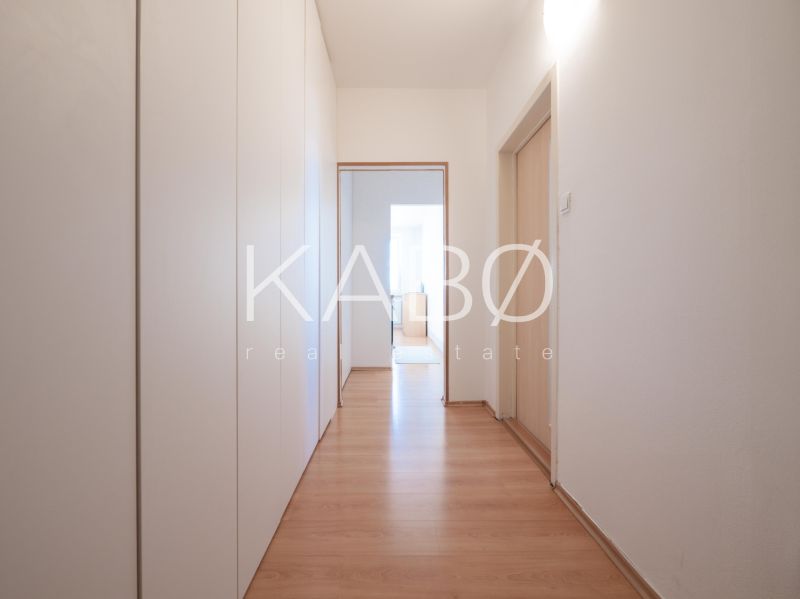 Der Flur in einer 2-Zimmer-Wohnung mit Schränken und einem Boden in Holzoptik.