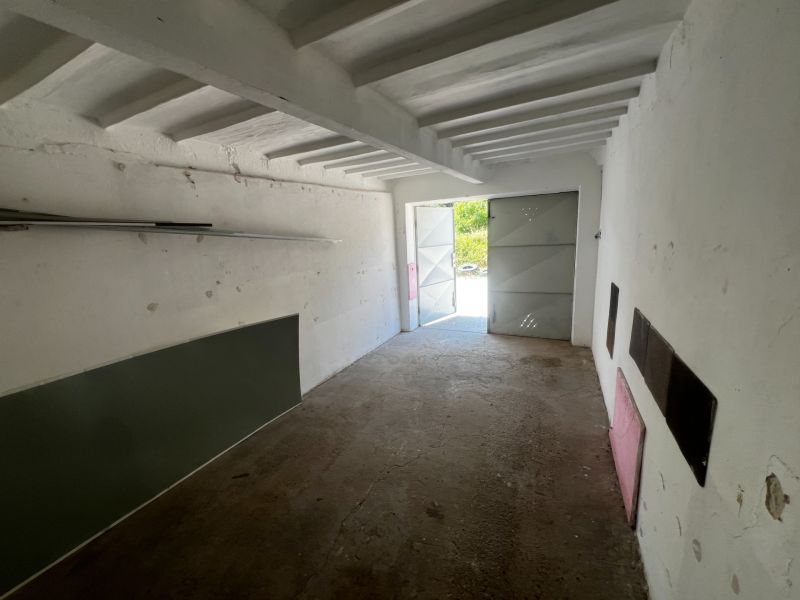 Innenraum einer Garage mit Betonboden und offenen Blechttüren.