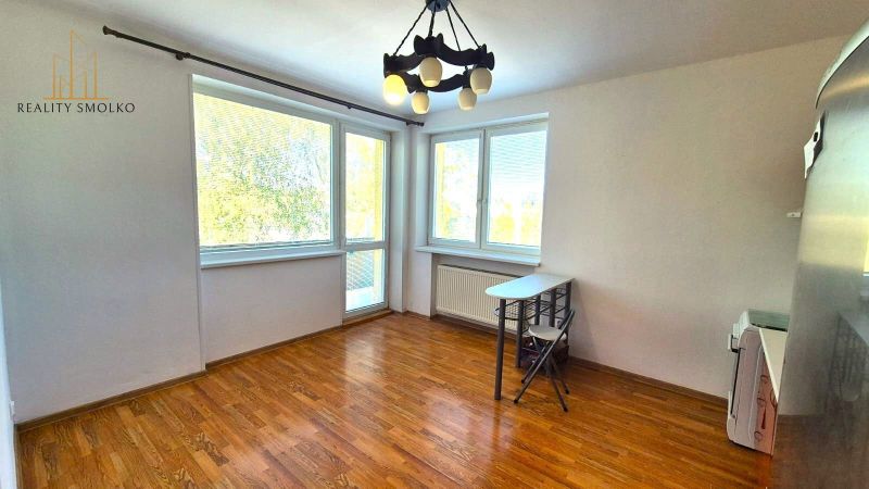 Ein Zimmer mit großen Fenstern und einem Holzboden in einer Einzimmerwohnung.
