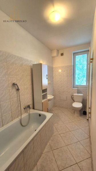 Badezimmer mit Badewanne und Fenster in einer Einzimmerwohnung, Fliesen und Kacheln.