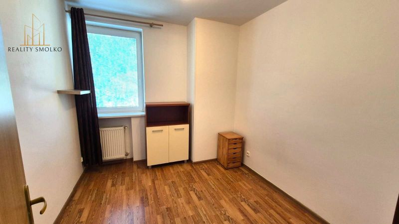 Ein Zimmer mit Holzboden in einer Einzimmerwohnung mit hellen Möbeln.