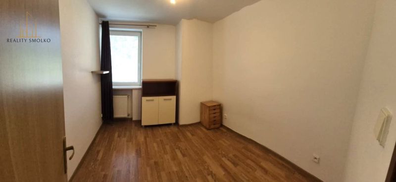 Einzimmerwohnung mit Holzboden, Möbeln und weißen Wänden.