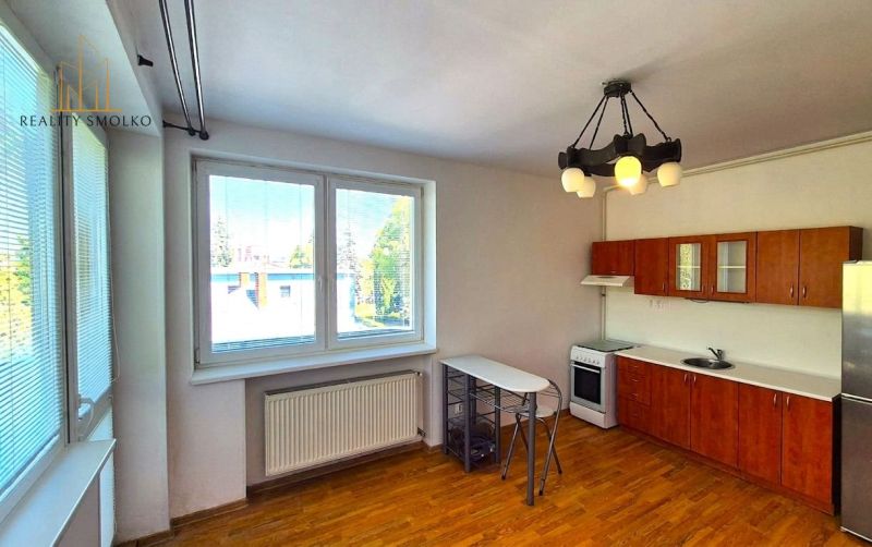 Küche in einer Einzimmerwohnung mit Platz für eine Essecke und einem Boden in Holzoptik.
