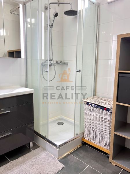 Badezimmer mit Dusche, Schrank und Wäschekorb in einer Zweizimmerwohnung.
