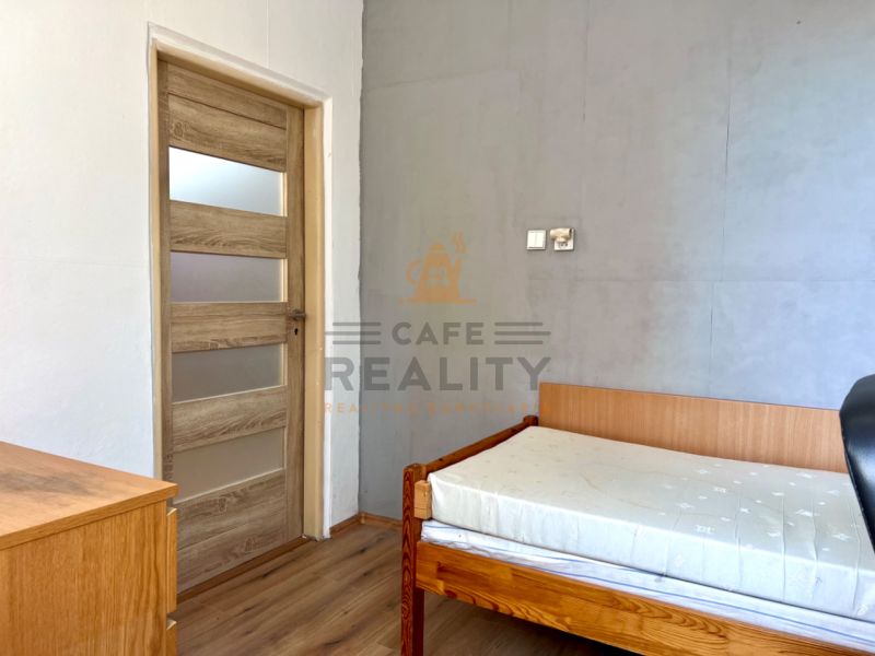 Ein Zimmer in einer 2-Zimmer-Wohnung mit einem Bett und einem Boden in Holzoptik.