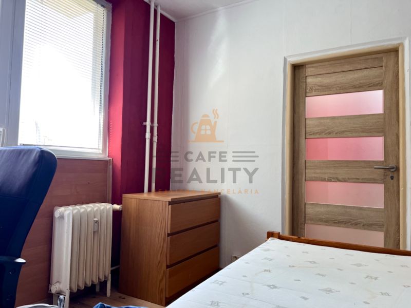 Ein Zimmer in einer 2-Zimmer-Wohnung mit Holzelementen, Möbeln und einem Heizkörper.