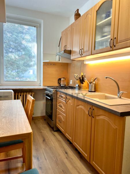 Küche in einer 2-Zimmer-Wohnung mit Holzmöbeln und einem Boden mit Holzdekor.