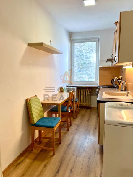 Küche mit zwei Stühlen und Holzboden in einer Zweizimmerwohnung.