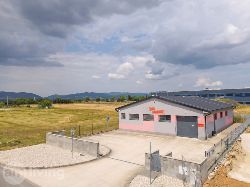 Ein Industriegebäude in Nová Dubnica, umgeben von Feldern und Bergen.