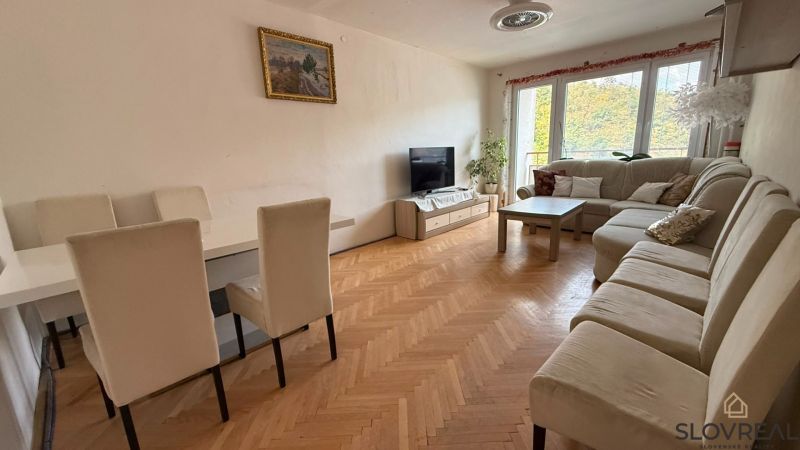 Wohnzimmer in einer 4-Zimmer-Wohnung mit großem Sofa, Esstisch und Holzboden.