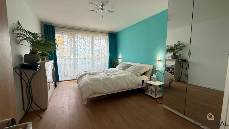Helles Schlafzimmer mit türkisfarbener Wand, Holzboden und Spiegelschrank in einer Vierzimmerwohnung.