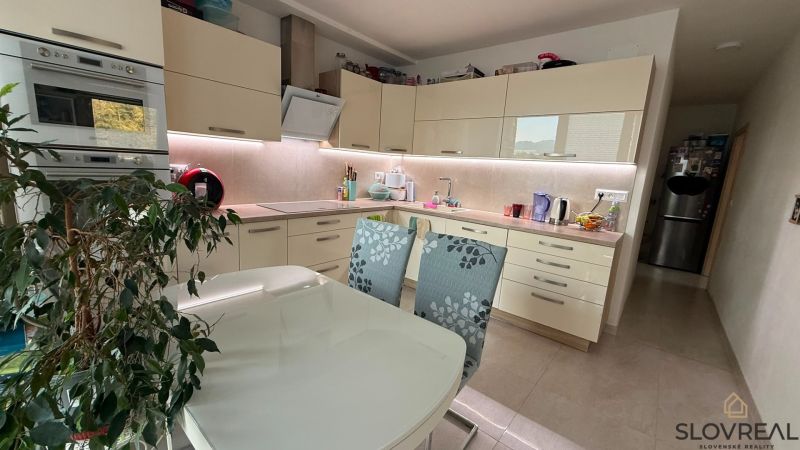 Küche in einer 4-Zimmer-Wohnung mit weißen Schränken und Esstisch.