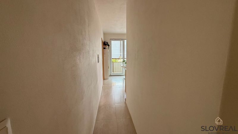 Ein enger Flur, der zu den Glastüren in einer 4-Zimmer-Wohnung führt.