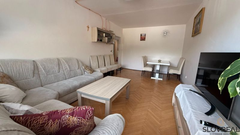 Wohnzimmer in einer 4-Zimmer-Wohnung mit einer bequemen Couchgarnitur und einem Boden in Holzoptik.