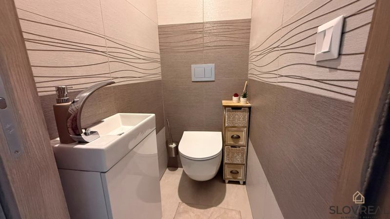 Gemütliche Toilette mit einfachem Waschbecken und dekorativen Fliesen in einer 4-Zimmer-Wohnung.