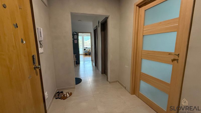 Ein Flur mit hellen Fliesen und Holztüren in einer Vierzimmerwohnung.