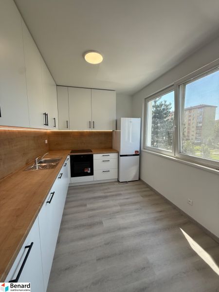 Küche in einer 3-Zimmer-Wohnung mit weißen Schränken und einem Boden in Holzoptik.