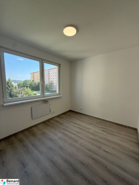 Ein Zimmer in einer 3-Zimmer-Wohnung mit einem Boden in Holzoptik und großen Fenstern.