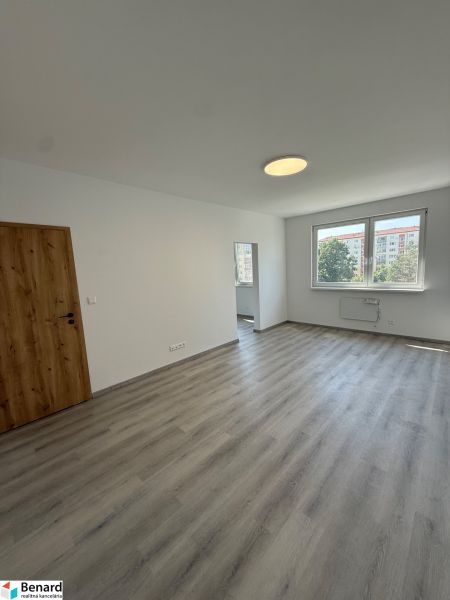 Zimmer in einer 3-Zimmer-Wohnung mit Holzboden, weißen Wänden und einem Fenster.