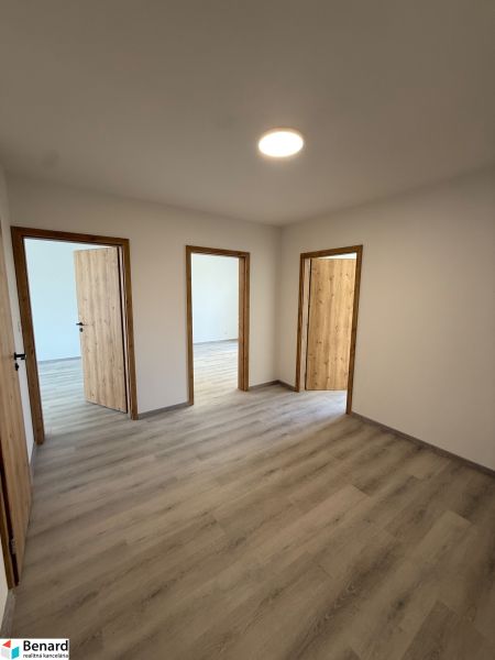 Ein Zimmer in einer 3-Zimmer-Wohnung mit einem Holzboden und drei Türen.