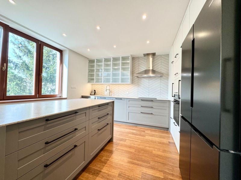 Helle Küche mit Kochfeld, Spüle und Boden mit Holzdekor in einer 3-Zimmer-Wohnung.