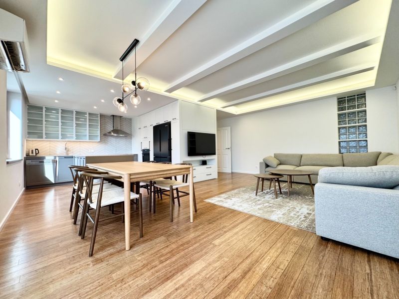 Wohnzimmer in einer 3-Zimmer-Wohnung mit Küche, Esstisch und Holzboden.