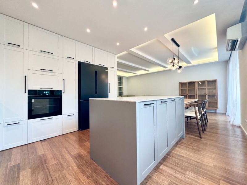 Küche mit Insel in einer 3-Zimmer-Wohnung, Boden mit Holzdekor, Esszimmer.