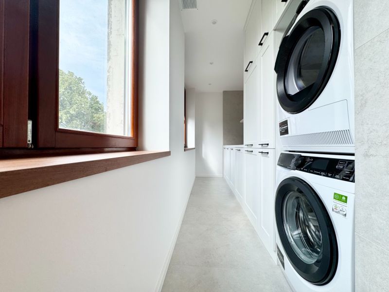 Praktische Waschküche in einer 3-Zimmer-Wohnung mit Waschmaschine und Trockner auf weißem Boden.
