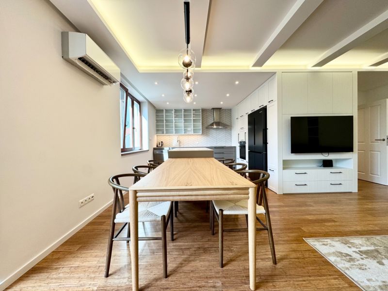Küche in einer 3-Zimmer-Wohnung mit Beleuchtung, Holzboden und Esstisch.