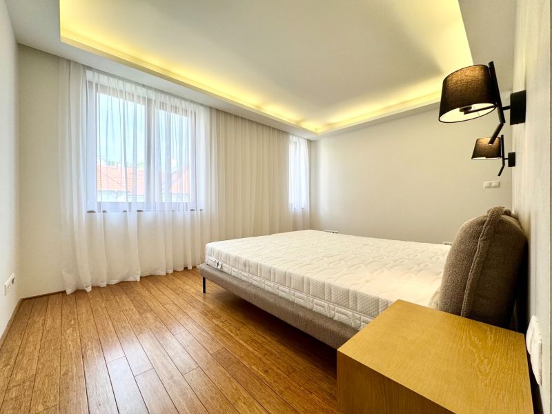Schlafzimmer in einer 3-Zimmer-Wohnung mit Vorhängen und einem Boden in Holzoptik.