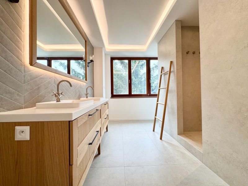 Badezimmer in einer 3-Zimmer-Wohnung mit Doppelwaschbecken und großem Fenster.