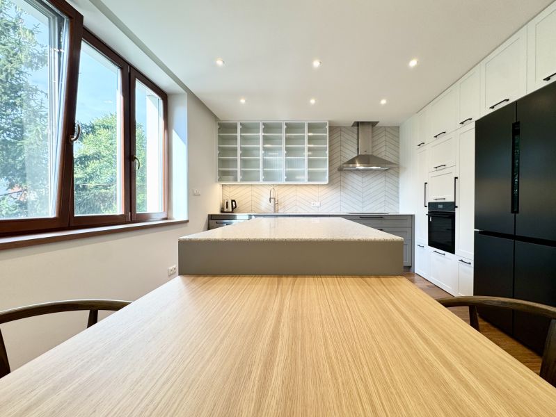 Küche in einer 3-Zimmer-Wohnung mit Insel und LED-Beleuchtung, Boden mit Holzdekor.