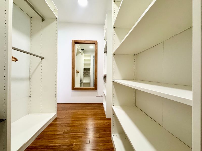 Ein Kleiderschrank in einer 3-Zimmer-Wohnung mit Regalen und einem Boden in Holzoptik.
