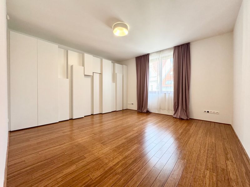 Ein geräumiges Zimmer in einer 3-Zimmer-Wohnung mit Holzboden und Einbauschränken.