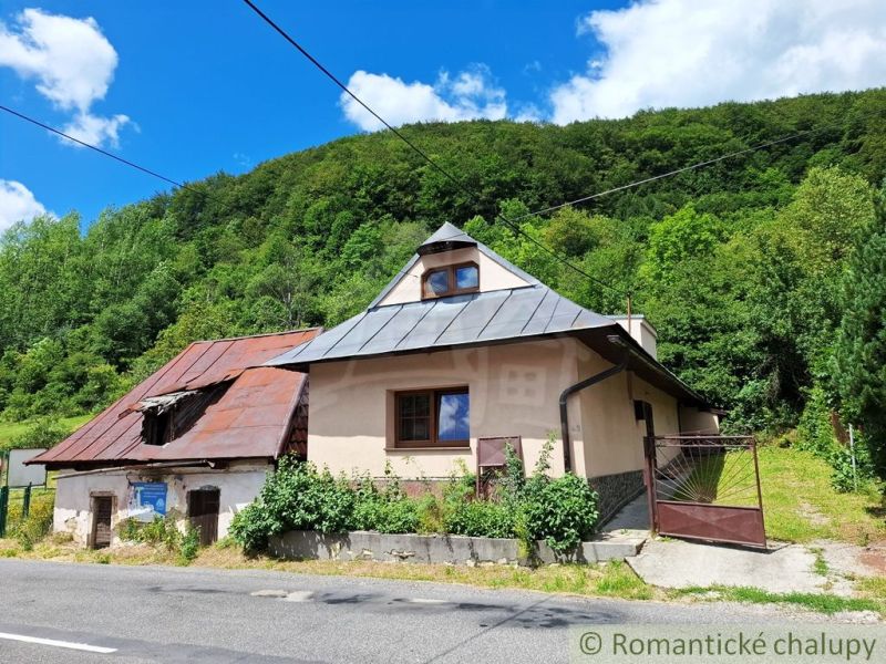 Ein älteres Haus mit Schrägdach in Mýto pod Ďumbierom, umgeben von Grün.