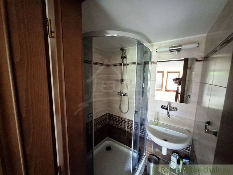 Badezimmer mit Duschkabine, Waschbecken und Spiegel.