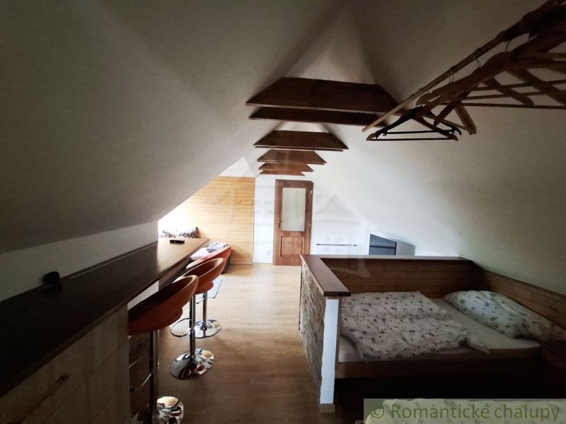 Dachbodenraum mit Bett, Bartheke und Boden mit Holzdekor.