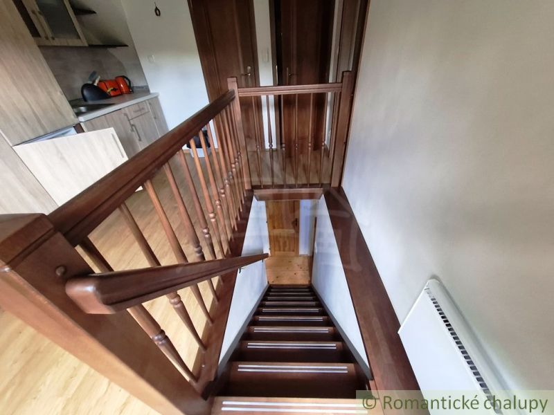 Ein Interieur mit einer Holztreppe neben der Küchenzeile und einem Boden mit Holzdekor.