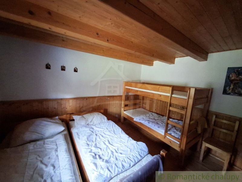 Ein Zimmer mit zwei Betten und einem Etagenbett, Holzwand- und Deckenverkleidung.