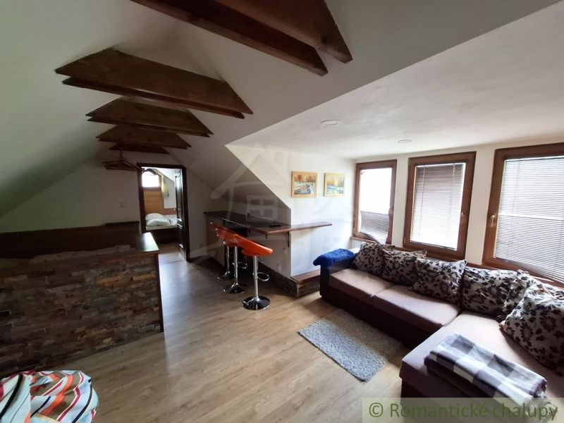 Dachgeschoss-Interieur mit Holzboden, Sitzgarnitur und Bartresen.