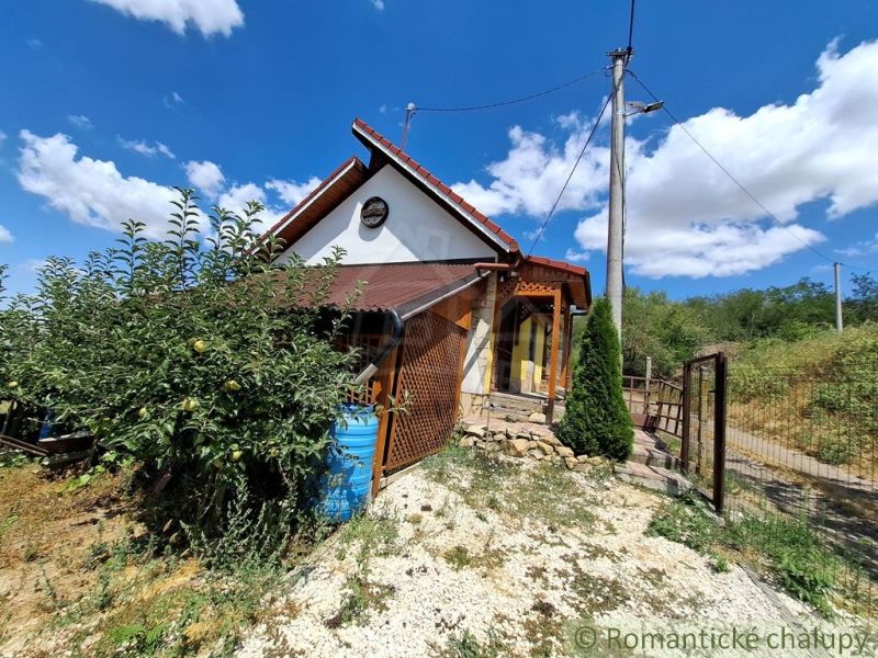 Eine Hütte in Gbelce, umgeben von Grün und Bäumen unter blauem Himmel.